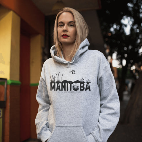 Featuring a prairie landscape, the design showcases wildflowers and prairie grasses blooming from the letters "Manitoba," artfully integrated into the scene.